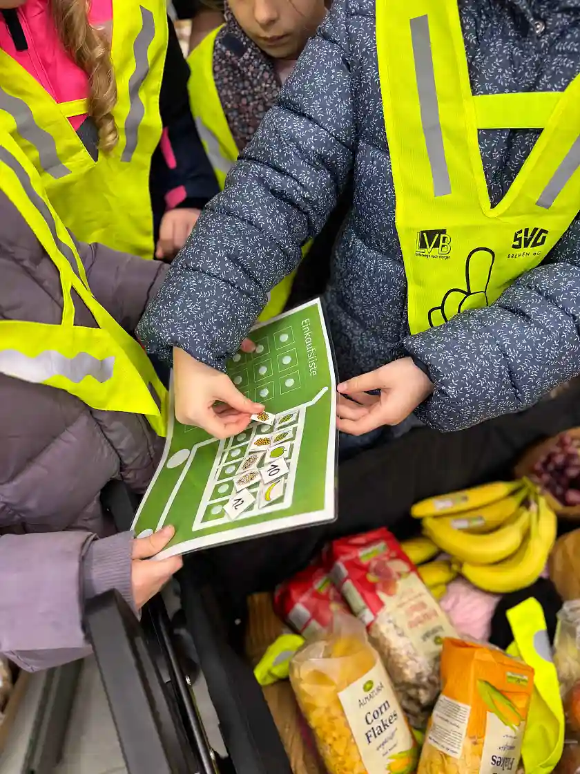 Kinder kleben Bilder der Lebensmittel, die sie schon in den Wagen gelegt haben, auf ihren Einkaufszettel
