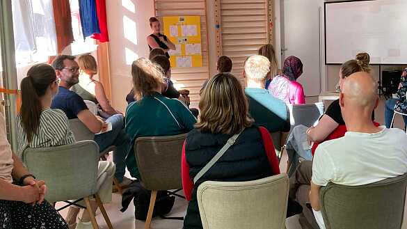 Eltern sitzen auf Stühlen von hinten fotografiert.