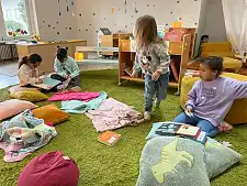 Kinder beschäftigen sich auf einem Teppich mit Büchern.