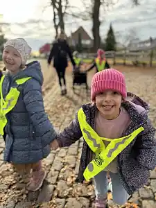 Zwei Kinder laufen an der Hand und grinsen in die Kammera