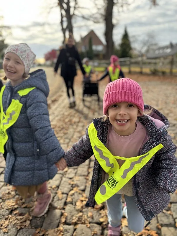 Zwei Kinder laufen an der Hand und grinsen in die Kammera