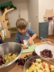 Junge schneidet Trauben auf einem Brettchen