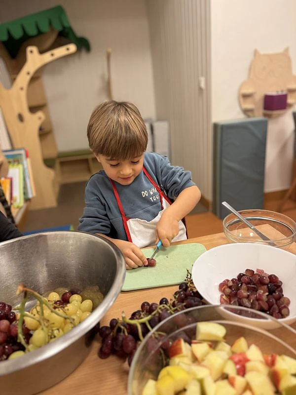 Junge schneidet Trauben auf einem Brettchen