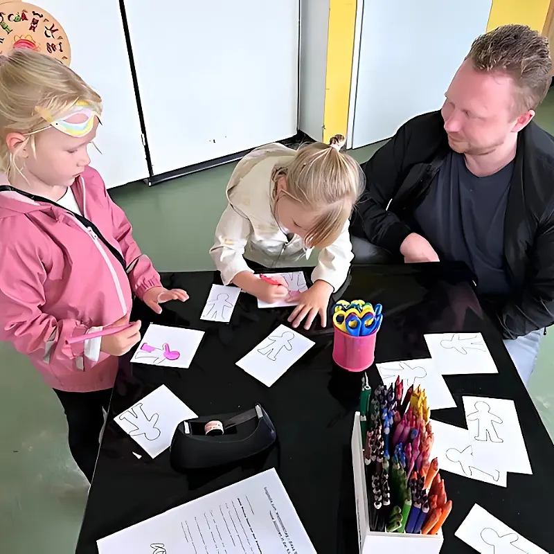 Vater mit zwei Kindern bastelt zum Thema Kinderrechte.