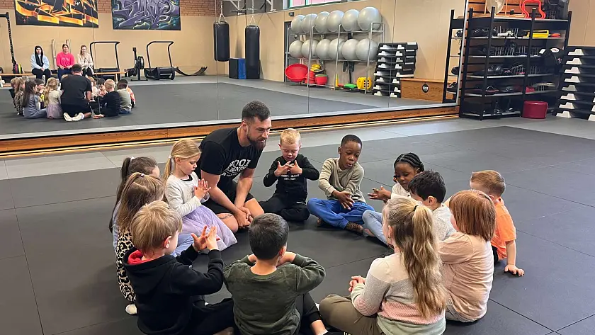 Gemeinsame Absprache: Kinder sitzen gemeinsam mit dem Trainer im Kreis auf dem Boden