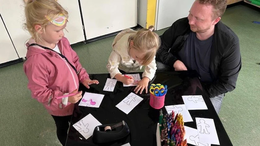 Vater bastelt mit seinen zwei Kindern zum Thema Kinderrechte