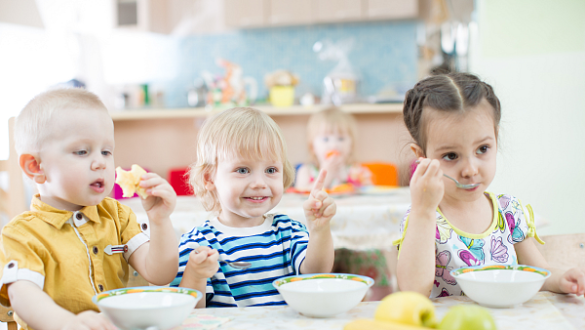 Drei Kinder sitzen am Tisch und essen Müsli