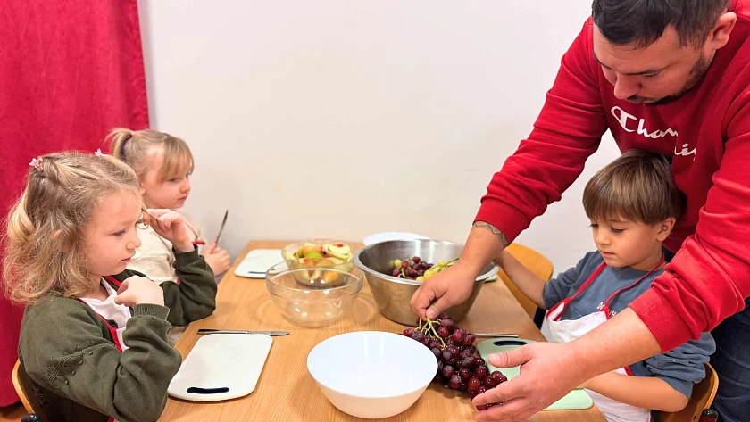 Drei Kinder sitzen am Tisch und sind bereit für die Frühstücksvorbereitungen.