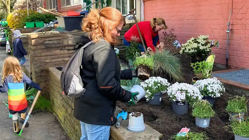 Kinder und Familien des Kinder- und Familienzentrums Löwenzahn beim bepflanzen des Hochbeetes vor der Tür.