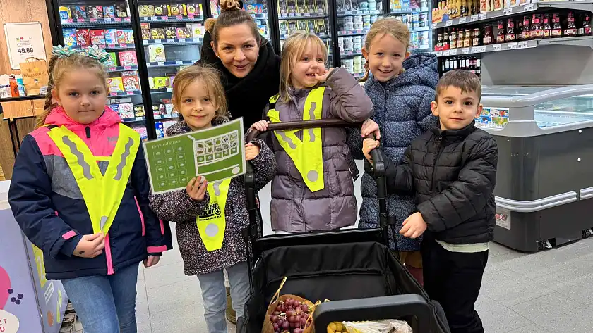 Gruppen von Kindern mit Erzieherin im Supermarkt