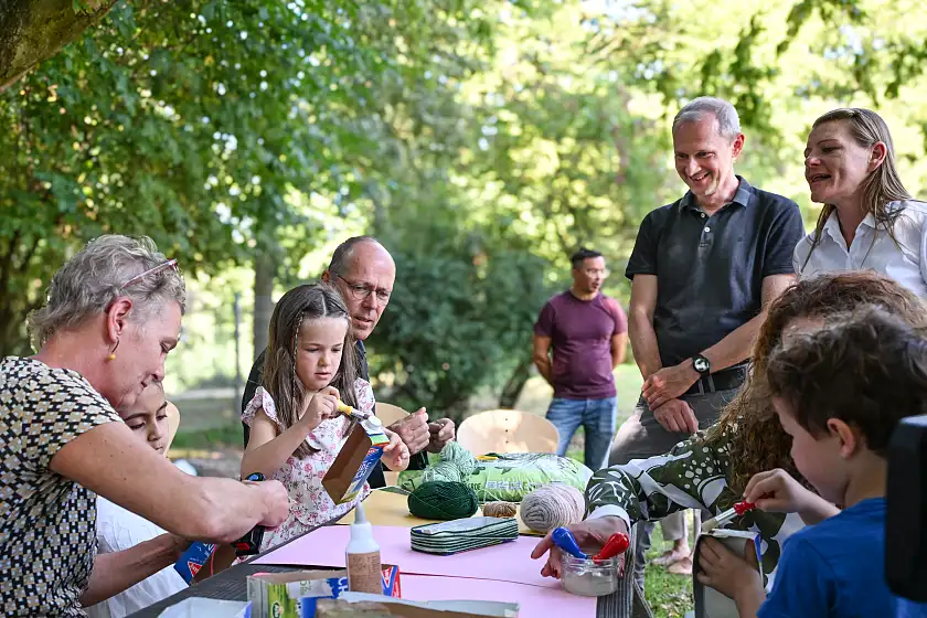 Erwachsene schauen Kindern beim Basteln zu