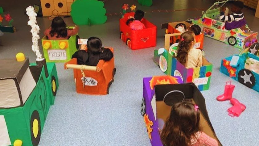Kinder sitzen in selbstgebastelten Autos aus Pappkartons