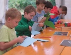 Workshop-Impression: Kinder stehen am Tisch und schneiden Papphände aus