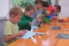 Workshop-Impression: Kinder stehen am Tisch und schneiden Papphände aus