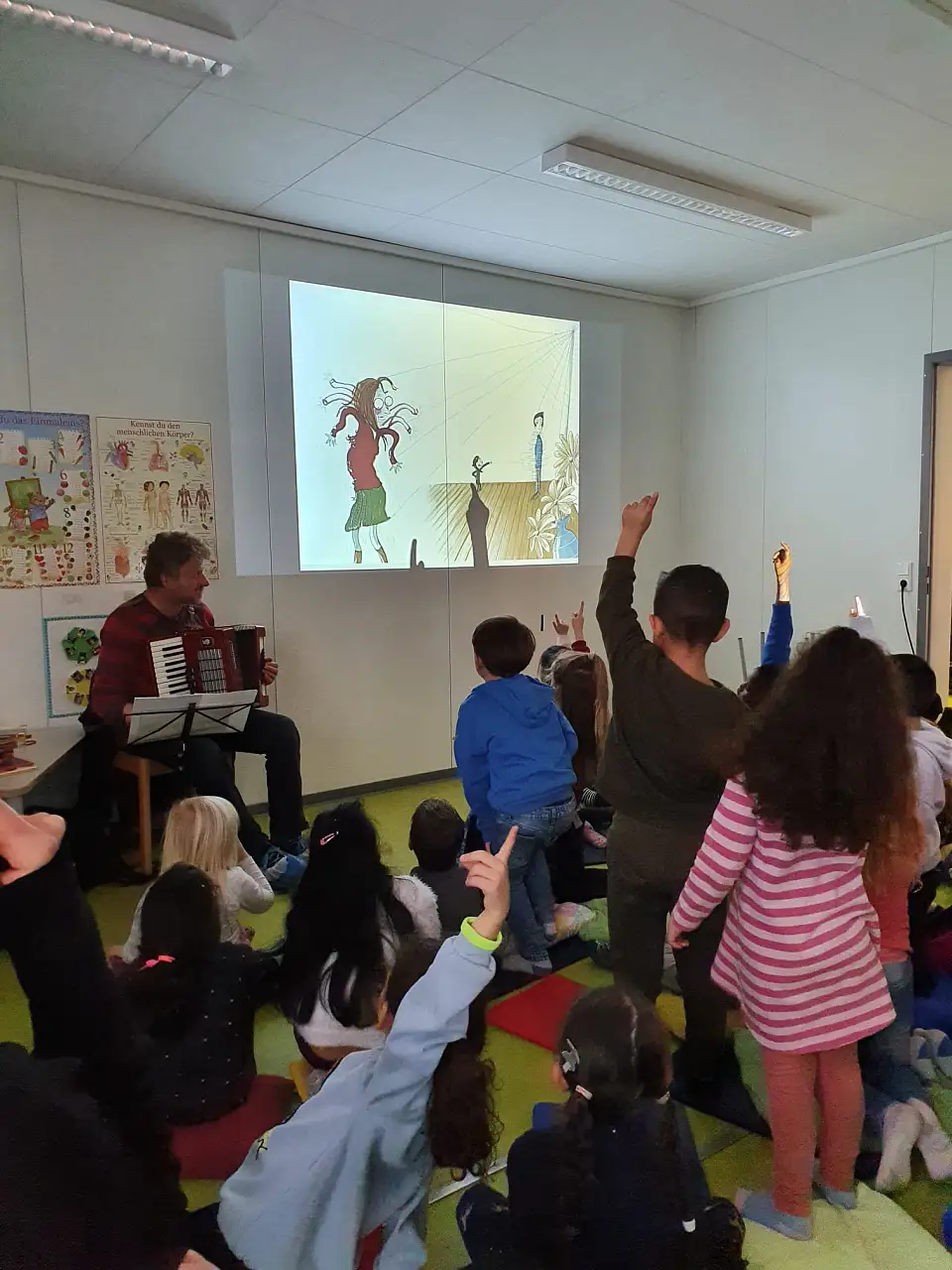 Eine Gruppe Kinder Sitz vor Autor mit Akkordeon in der Hand.