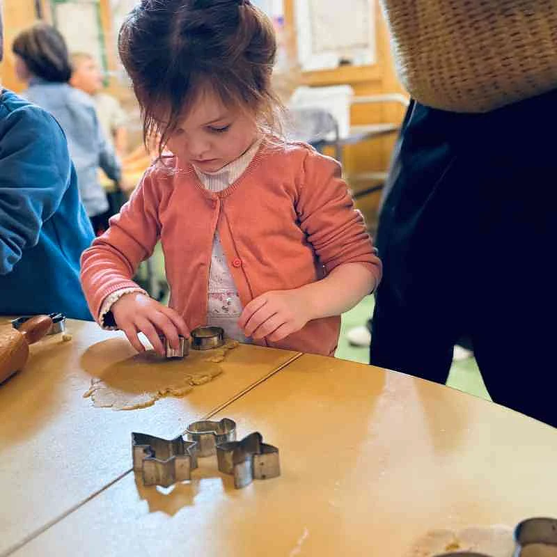 Ein Kind sticht Kekse aus einem ausgerollten Teig aus.