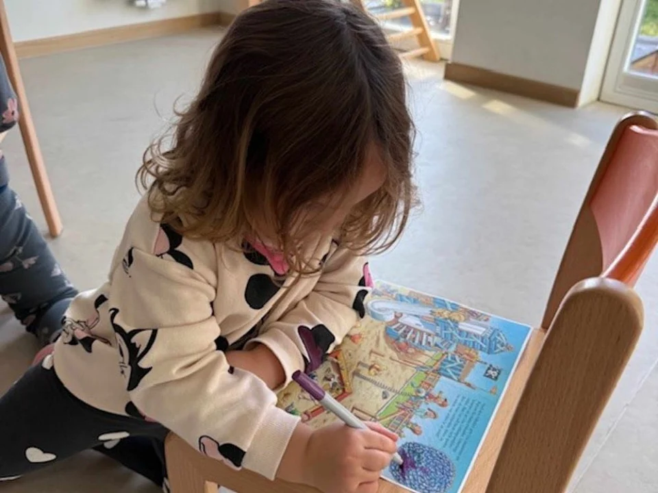 Kind sucht Fehler im Buch, das auf einem Stuhl liegt.