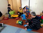 Väter mit Ihren Kindern bauen auf dem Spieleteppich im Kindergarten