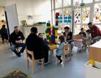 Väter und Kinder sitzen im Kindergarten an Tischen unterhalten sich