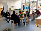 Väter und Kinder sitzen im Kindergarten an Tischen unterhalten sich