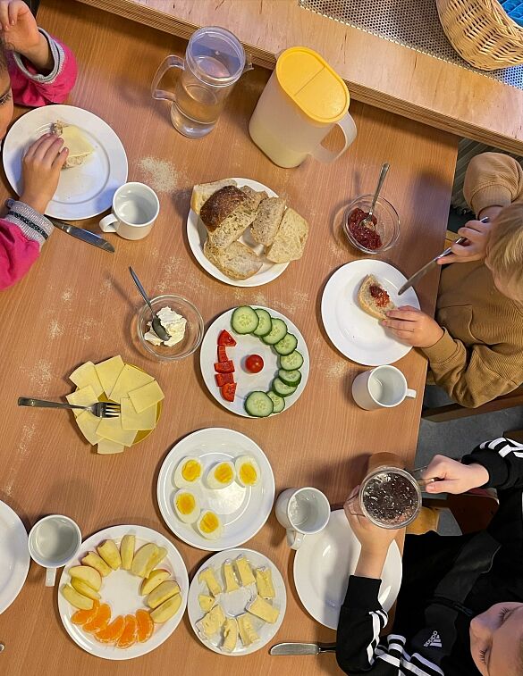 Tisch mit Tellern voll Obst und Brötchen 