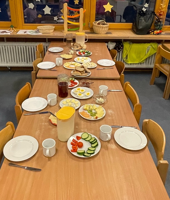 Tisch mit Tellern voll Obst und Brötchen 