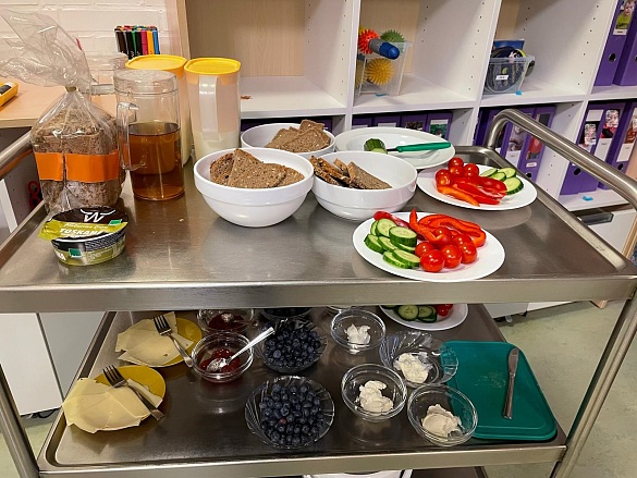 Wagen mit vorbereitetem Frühstück: Schwarzbrot, Joghurt, Blaubeeren, Gurkenscheiben, Paprika