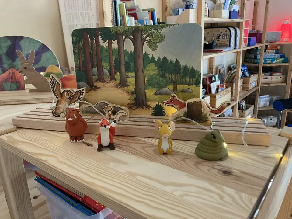 Figuren bekannter Kinderb&uuml;cher stehen vor einem Bild, das den Hintergrund der Figurenaufstellung darstellt