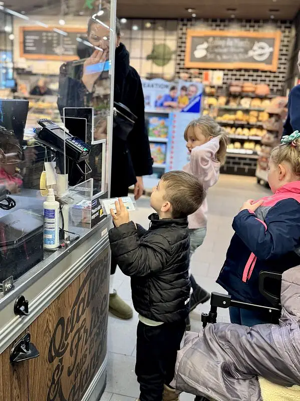 Kleines Kind steht vor Kasse zum Bezahlen.