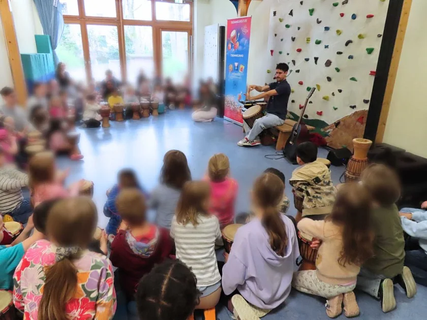 Kinder sitzen in der Turnhalle und musizieren gemeinsam