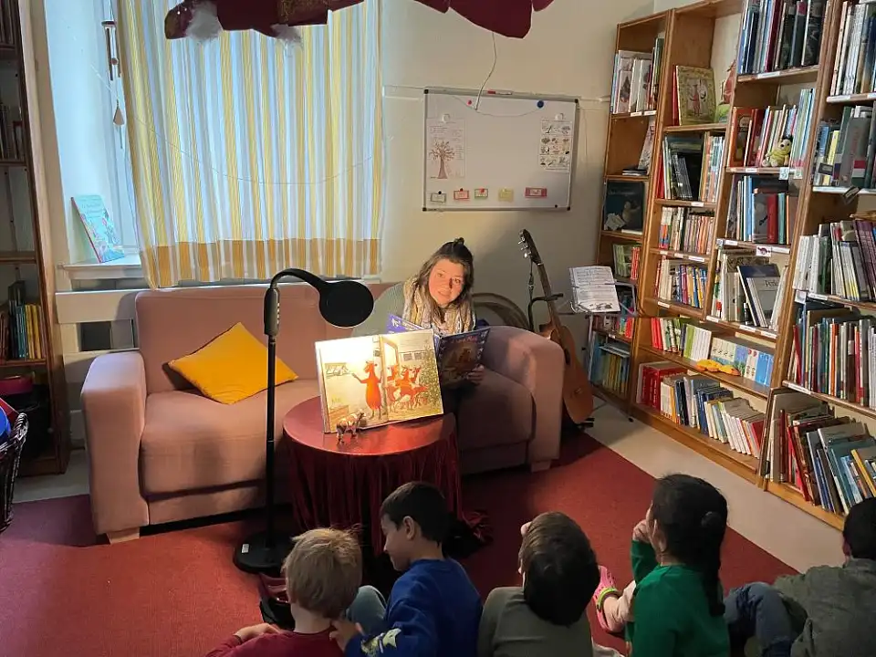 Erzieherin lie&szlig;t einer kleinen Gruppe von Kindern "Mama Muh" vor.