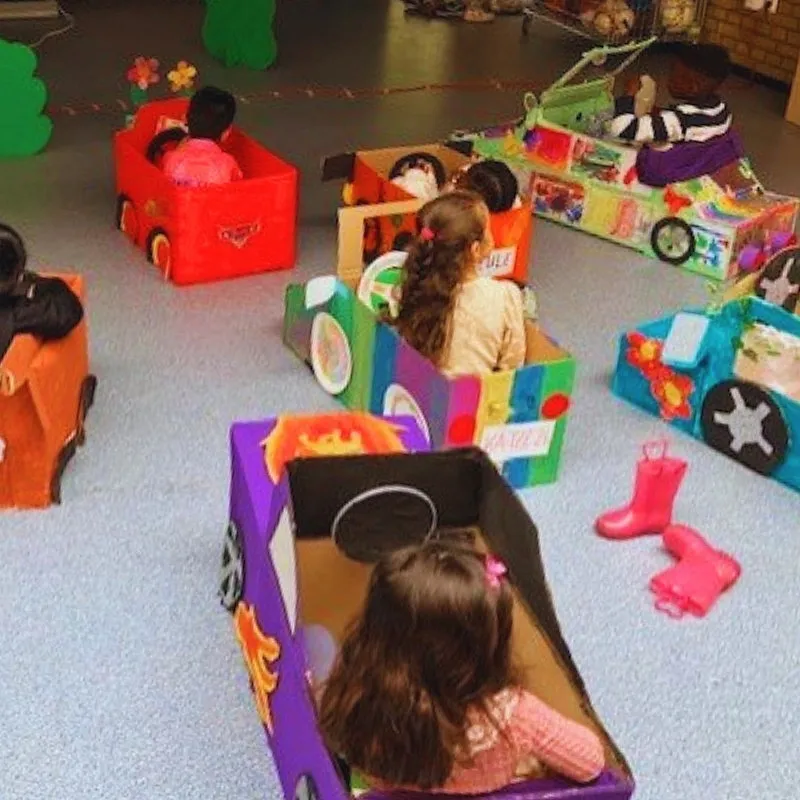 Kindern sitzen in selbstgebastelten Autos aus Pappkarton
