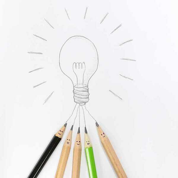 Bleistiftspitzen mit kleinen, lachenden Gesichtern zeigen auf eine gezeichnete Glühbirne