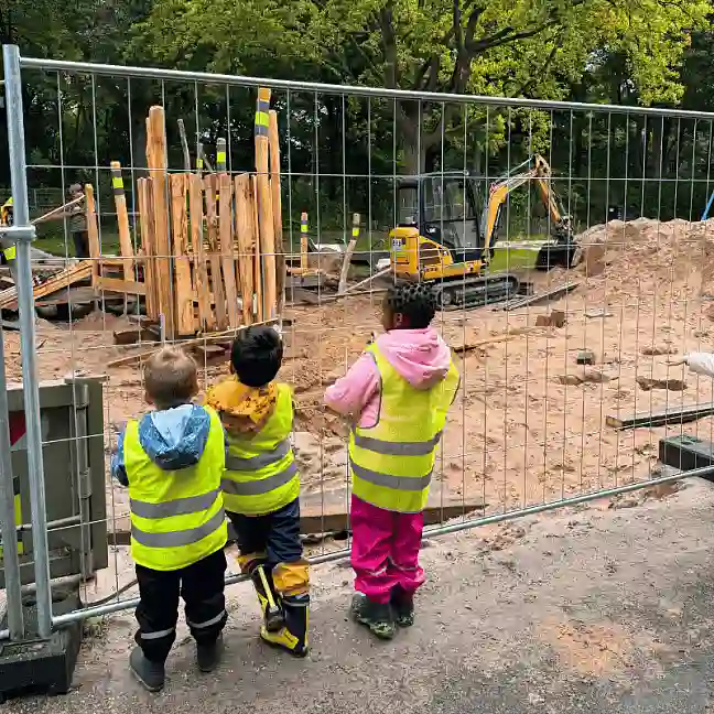 Kinder warten am Bauzaun auf die Fertigstellung des Spielplatzes