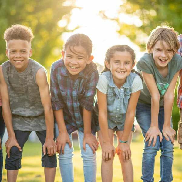 Kinder stehen auf einer Wiese und strahlen in die Kamera